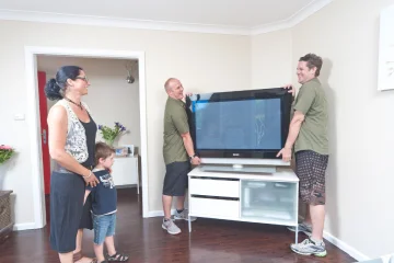 Furniture removals team from Man and His Van safely moving a fragile television with care during a residential move in Sydney.