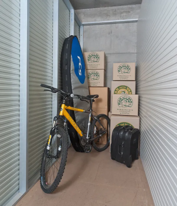 A well-organised storage unit in Sydney’s Northern Beaches, featuring a bicycle, packed moving boxes, and travel luggage, demonstrating secure, clean storage solutions.
