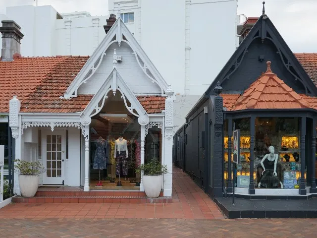 Two boutique shopfronts with decorative gables, tiled roofs and clothing displays
