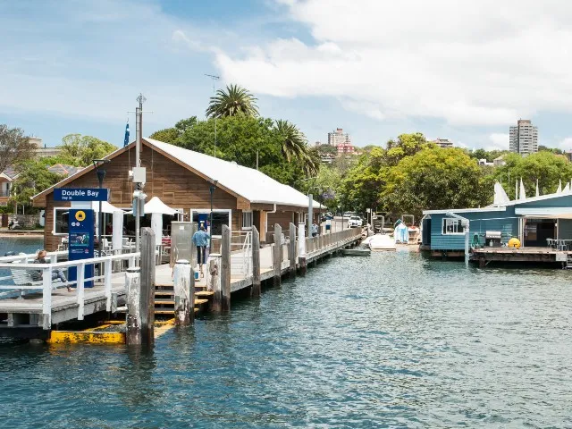Double Bay ferry wharf with a timber terminal building, boarding walkway and surrounding harbour
