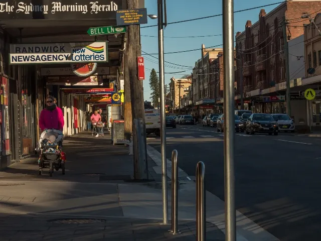 Randwick shopping street with a newsagency, covered footpaths, pedestrians and parked cars
