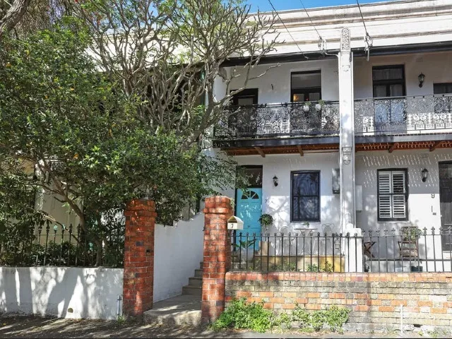 Two-storey terrace houses with decorative iron balconies, front gardens and a blue entrance door